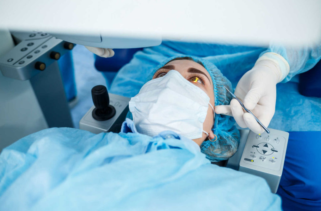 A woman in a blue surgical gown is undergoing LASIK eye surgery to reshape the cornea and correct the refractive error. LASIK is one of the more popular and commonly performed laser eye surgeries.