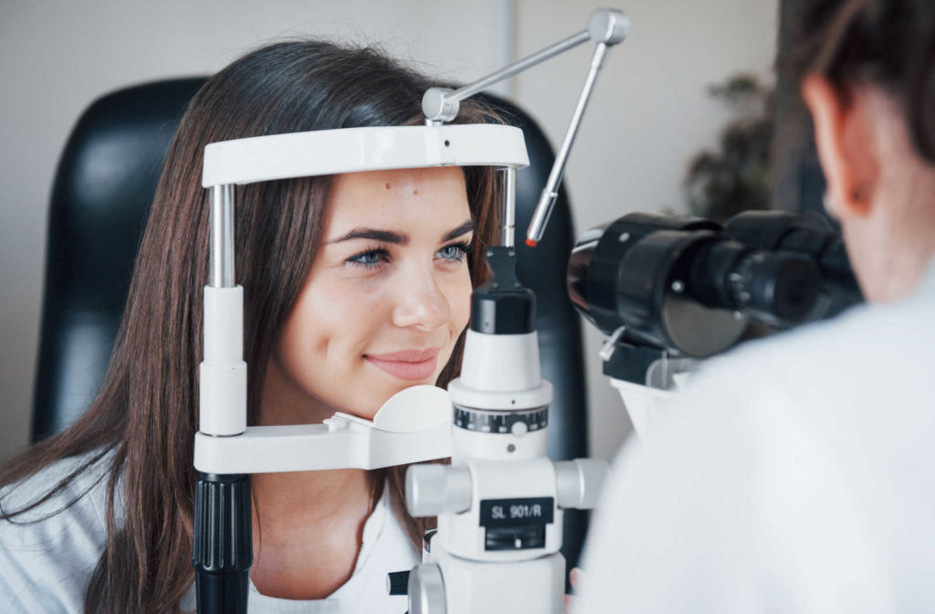 An optometrist examines a female patient with a slit lamp.