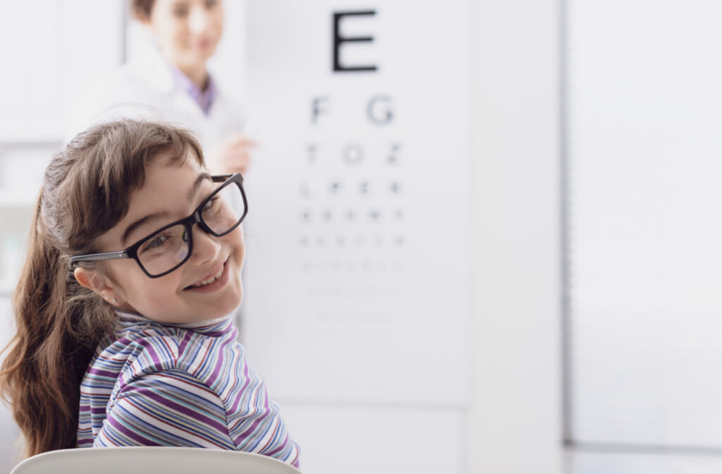 An optometrist conducting an eye exam on a female child with glasses.