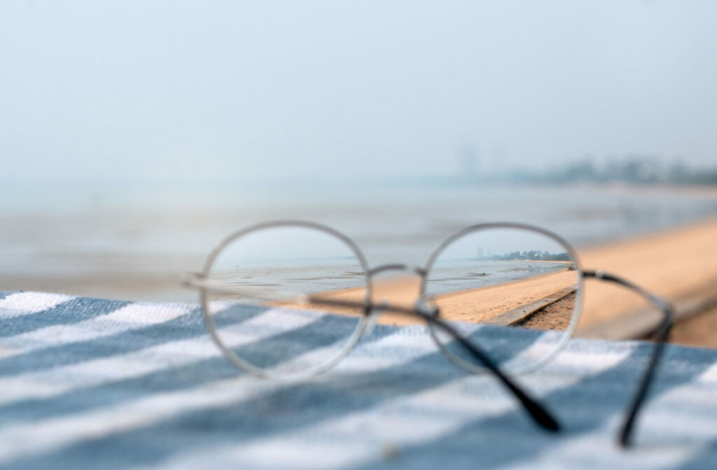 A pair of glasses show a clear beach backdrop while the image around the lenses is blurred.