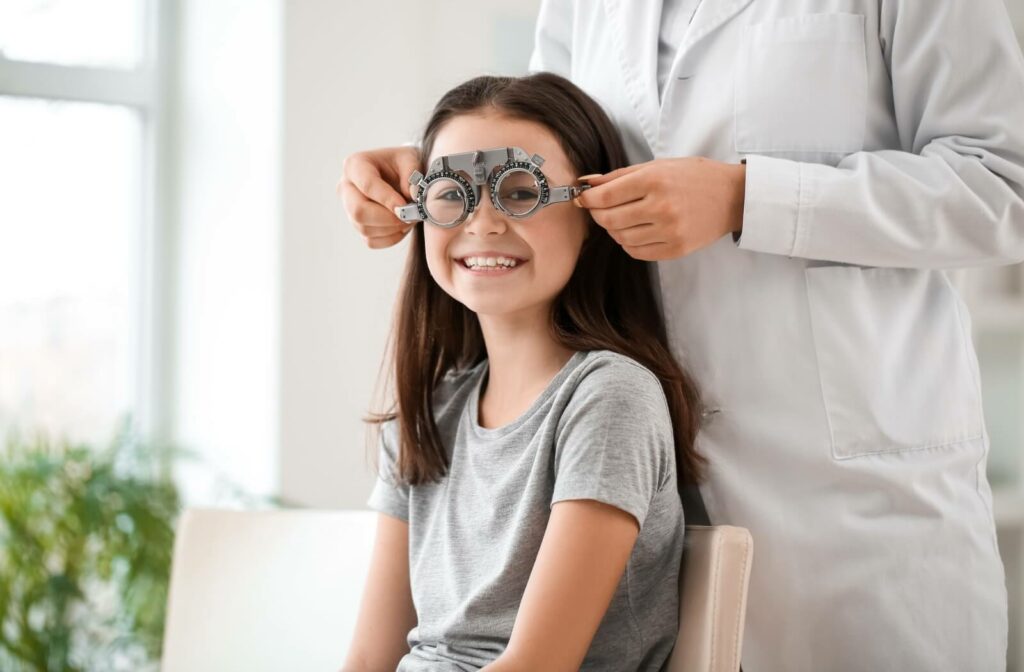 An optometrist uses eye test glasses on a happy child.