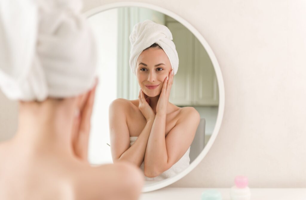 A happy patient inspects their rejuvenated skin in their mirror at home.