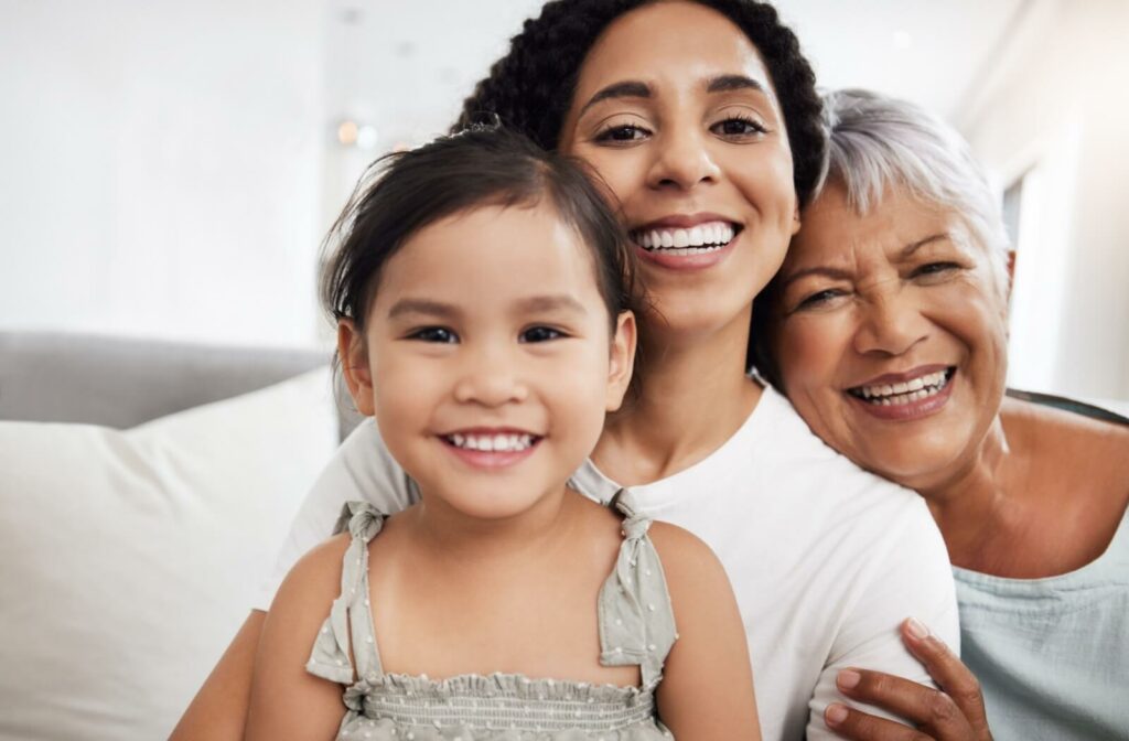 A young child smiling in front of their parent and grandparent, illustrating the visual changes that happen over time.