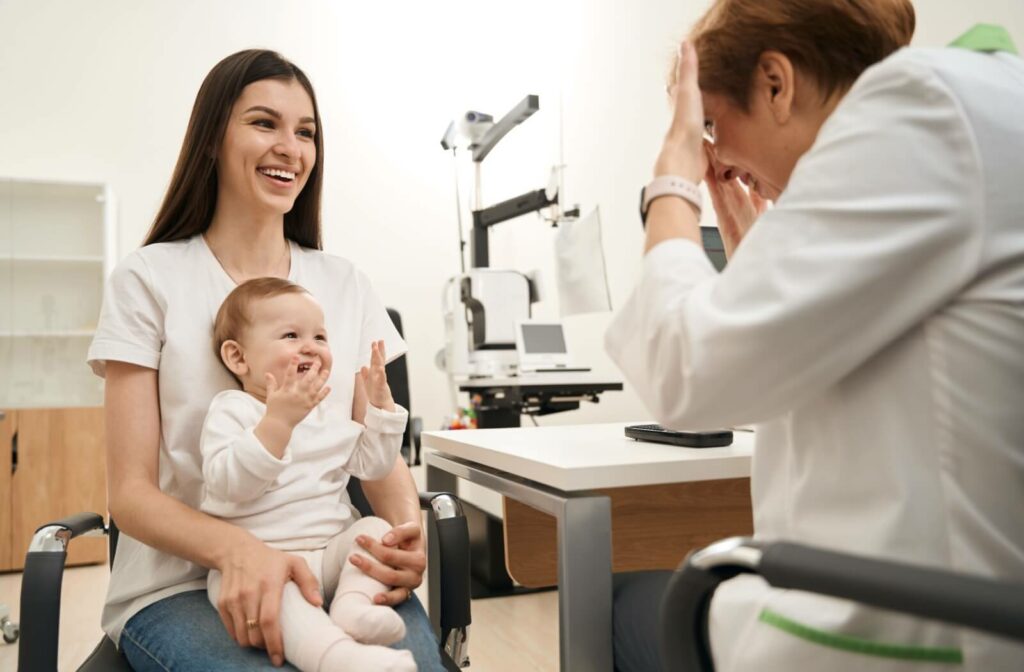 An infant sitting in their parent's lap has fun with their optometrist during their first eye exam.