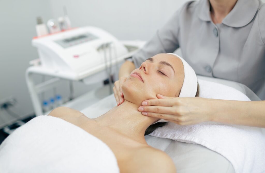 Person receiving a relaxing facial treatment while lying on a med spa table in a bright and modern clinic.